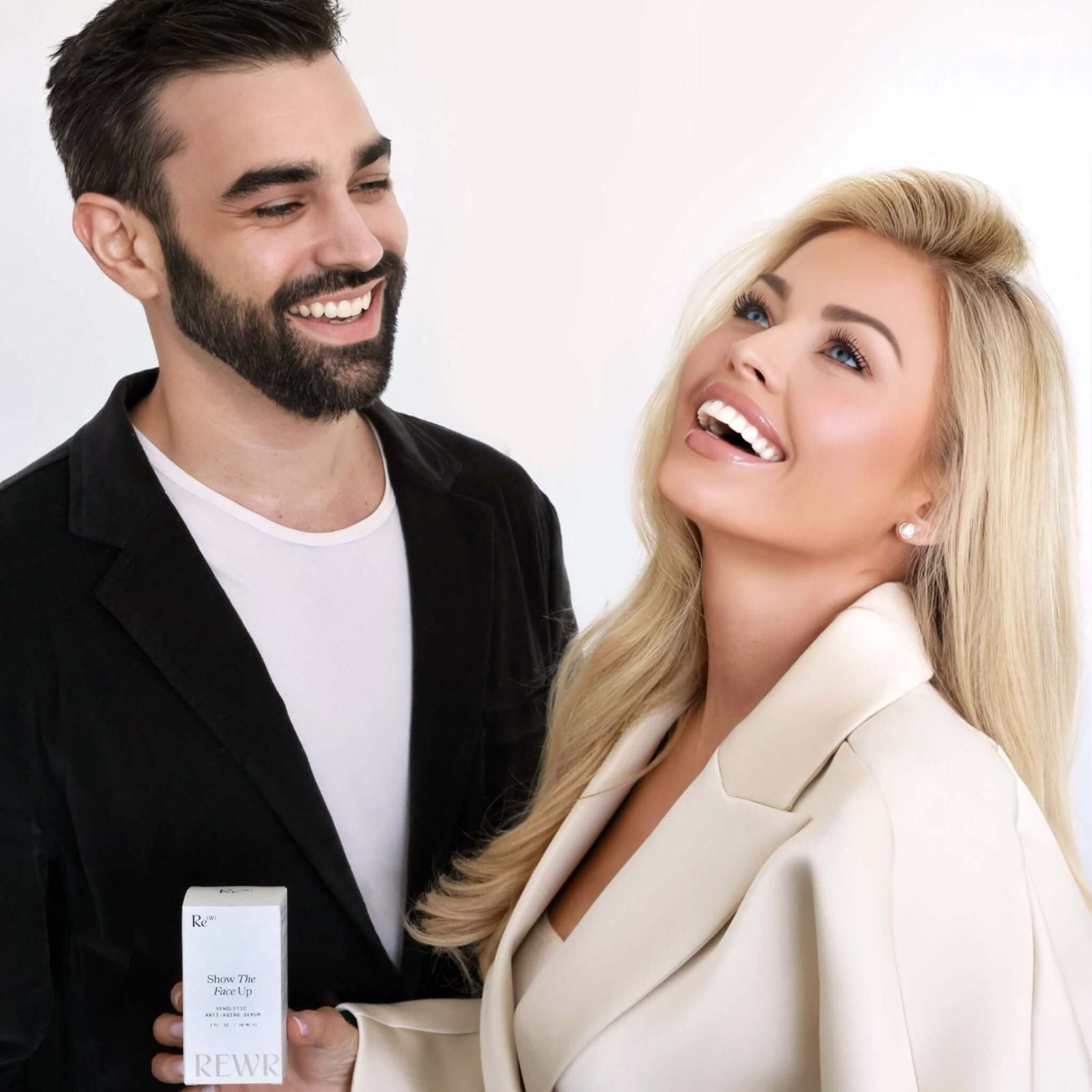 Rewritten Beauty founders Cynthia Garcia and Zak Garcia smiling together while holding the Show The Face Up serum product